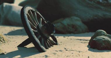CGI Old wooden wagon wheel resting in sand near rocks by the shore video