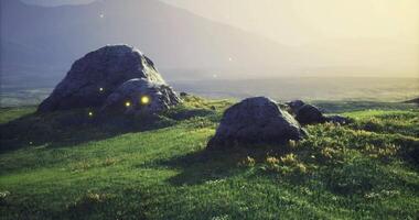 CGI Boulders on a serene grassy field during golden hour with distant mountains video