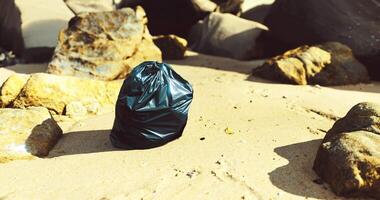 CGI Trash bag left on a sandy beach surrounded by rocks during daylight hours video