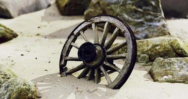 CGI Old wooden wheel partially buried in sandy beach surrounded by rocks video