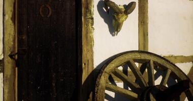 CGI Old wooden wheel and skull decorate rustic building in rural setting video