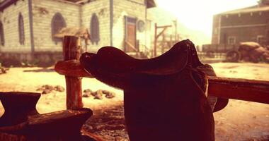 CGI Saddle hanging on wooden fence in a rustic western town during sunset video