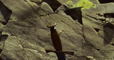 CGI Ancient sword resting on rocky surface in mysterious setting at dusk video