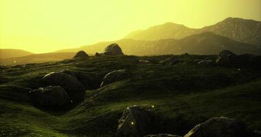 CGI Golden sunset over tranquil hills with scattered boulders and glowing insects video