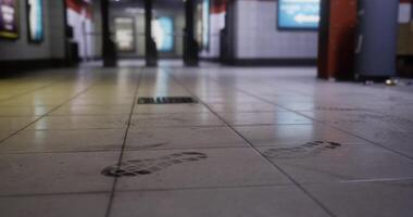 CGI Footprints on the tiled floor of a subway station in a busy urban area video