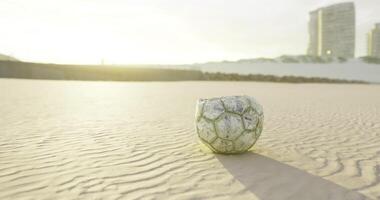 CGI Soccer ball resting on the sand during sunrise at a coastal location video
