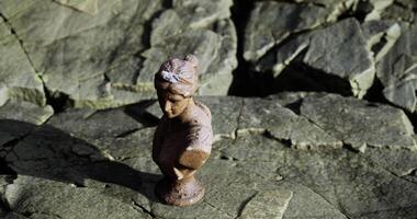 CGI Small statue resting on rocky surface next to the sea video