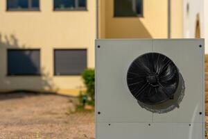Cooling unit stands ready beside modern building under warm sunlight, showcasing efficient energy solutions in urban environment photo