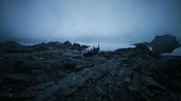 CGI Broken boat rests on rocky shore under a misty twilight sky video