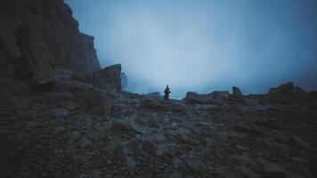 CGI Mysterious figure stands among rocky terrain during foggy twilight hours video