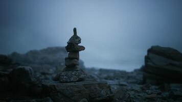 CGI Stacked stones on a rugged coastline during a foggy evening video