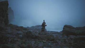 CGI Sculpture of stacked stones on a rocky shore during a foggy evening video