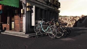 CGI Bicycles parked outside a rustic building by the shore at sunset video