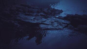 CGI Rocks submerged in calm dark water during twilight hours video
