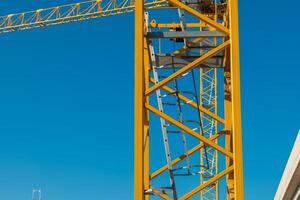Construction tower crane stands tall against a clear blue sky, showcasing intricate details of industrial architecture and engineering photo