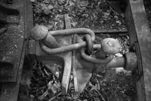 Rusty coupling on abandoned railway tracks showcases forgotten transportation history and nature's slow reclaiming photo