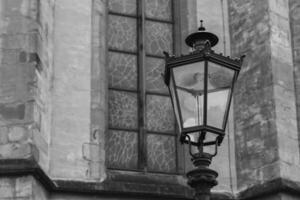 Stately lantern standing beside intricate stained glass on an ancient church wall at dusk photo