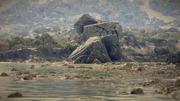 CGI Calm riverbank view with large boulders and gentle ripples at twilight video