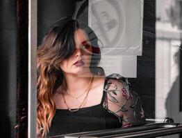 Young woman gazing thoughtfully through a window in an urban setting during daylight hours photo