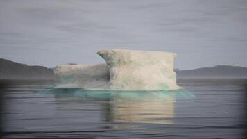 CGI Melting iceberg floating in calm waters near coastal landscape at dawn video