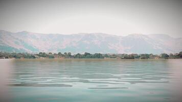 CGI Tranquil lake with mountain backdrop and calm water reflecting the sky video