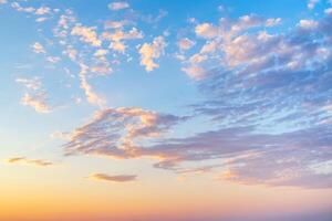 sky with wispy cirrus clouds illuminated by the setting sun in soft orange tones. Celestial landscape photo