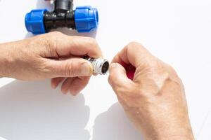closeup of hands assembling metal threaded part with plastic fittings, winding fumka, sealing tape photo