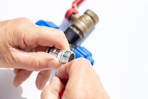 close-up of hands assembling metal threaded part with plastic fittings and valve, winding fumka, sealing tape photo