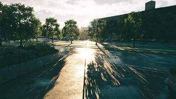 CGI Sunlight streaming through trees over a wet street in an urban setting video