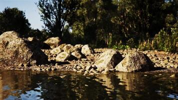 CGI Tranquil riverside landscape featuring rocks and reflections during golden hour video
