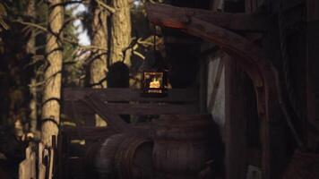 CGI Warm lantern glowing softly beside wooden structures in a forest setting video