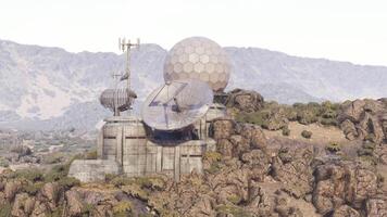 CGI Remote communication facility on rocky terrain with mountains in background video