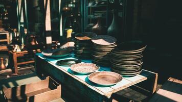 CGI Stacked plates on a wooden table in a sunlit artisan market setting video