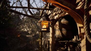 CGI Lantern hanging by rustic cabin in wooded area at sunset video