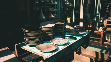 CGI Stacked plates on a wooden table in a bustling marketplace in the afternoon video