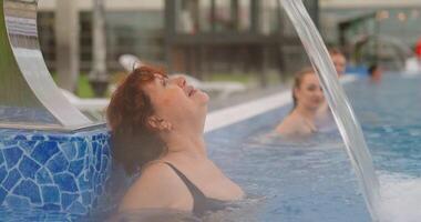 Relaxation In Modern Public Baths In SPA Center, Aged Woman Lying In Water Of Outdoor Swimming Pool video