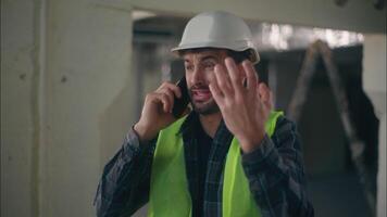 Annoyed Caucasian man contractor holding mobile phone speaking remote call conflict in construction builder foreman arguing furious guy technician building industry working problem upset male argument video