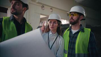 Three professional Caucasian builders colleagues discussing blueprint building in construction controller foremen holding draft engineers men radio set woman talking architects constructing teamwork video