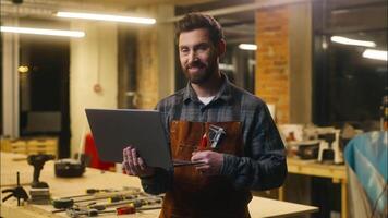Cheerful Caucasian man carpenter typing laptop showing thumb up sign in workshop wood master male worker artist using Internet delivery app online glad architect guy recommend craftsman satisfaction video