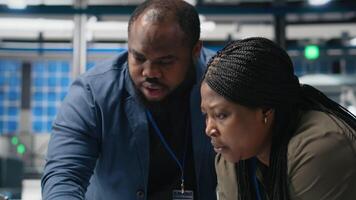 African american specialists supervisors examining production metrics on papers, supporting industrial innovation and alternative energy manufacturing process. Solar power. Camera A. video