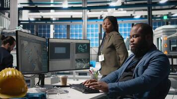 African american master engineers examining photovoltaics activity in solar power factory, reviewing data and checklists for the manufacturing process. Eco friendly renewable energy. Camera B. video