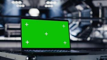 Green screen laptop inside futuristic spacecraft bay next to nearby monitor displaying Mars dashboard system telemetry. Mockup notebook used for navigation to red planet during orbital mission video