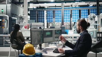 Male industrial expert monitoring high tech production line with modern equipment and performance metrics, clean energy manufacturing operations. Young business analyst engineer. Camera B. video