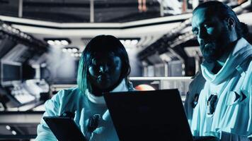Astronaut discussing with colleague, conducting scientific experiments during space mission. Teamworking cosmonauts performing controlled tests in space during mankind survival expedition, camera B video