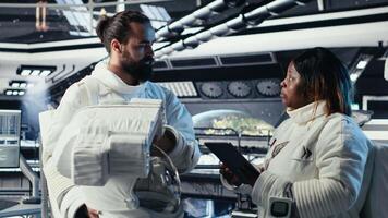 Astronaut putting helmet on and getting mission briefing from leader before stepping out of space station. Cosmonaut preparing to leave starship after landing on planet, saluting coworker, camera B video