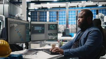African american supervisor checking solar panel machinery and reviewing a checklist, playing a vital role in renewable energy production and assembly line. Solar tech infrastructure. Camera B. video