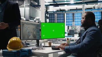 Male tech specialist reviewing assembly line next to mockup on pc, manages factory operations in solar power plant to ensure effective quality control and commitment for green energy. Camera B. video