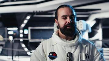 Cheerful astronaut doing videocall with Earth command center while aboard orbit station, sharing mission update. Happy cosmonaut talks with ground center team during communication link, camera B video