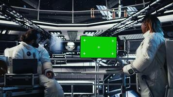 Astronaut reviewing onboard analytics on green screen monitor before stepping outside space station. Cosmonaut verifying parameters on mockup display after landing on planet, camera A video