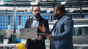 Diverse team of engineers and specialists collaborate in a solar panel factory, review blueprints and share ideas to enhance renewable energy production and sustainable innovation. Camera A. video